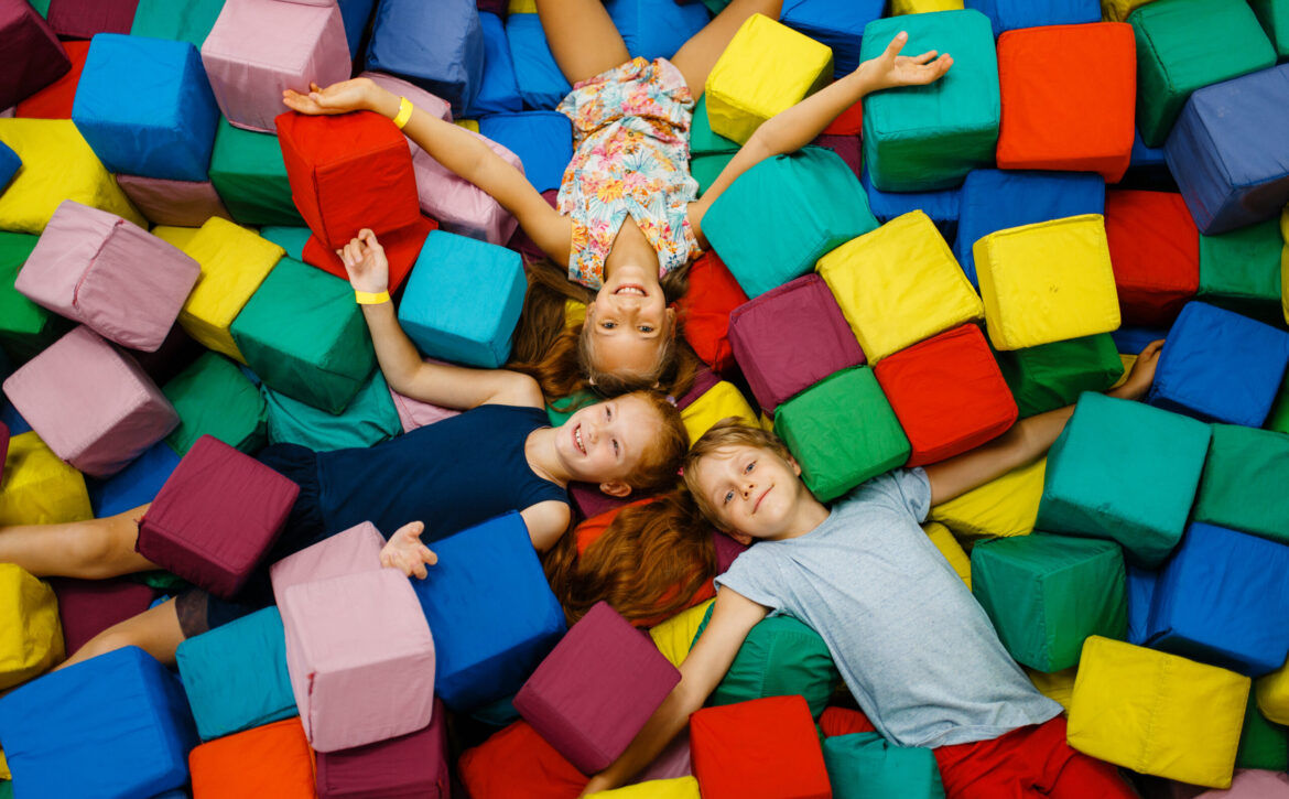 Happy children lying in soft cubes, playroom