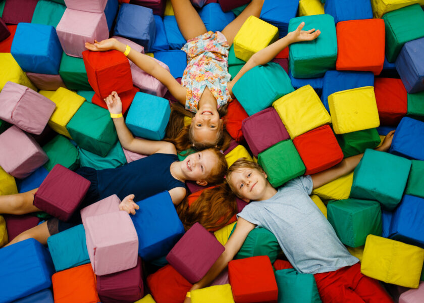 Happy children lying in soft cubes, playroom