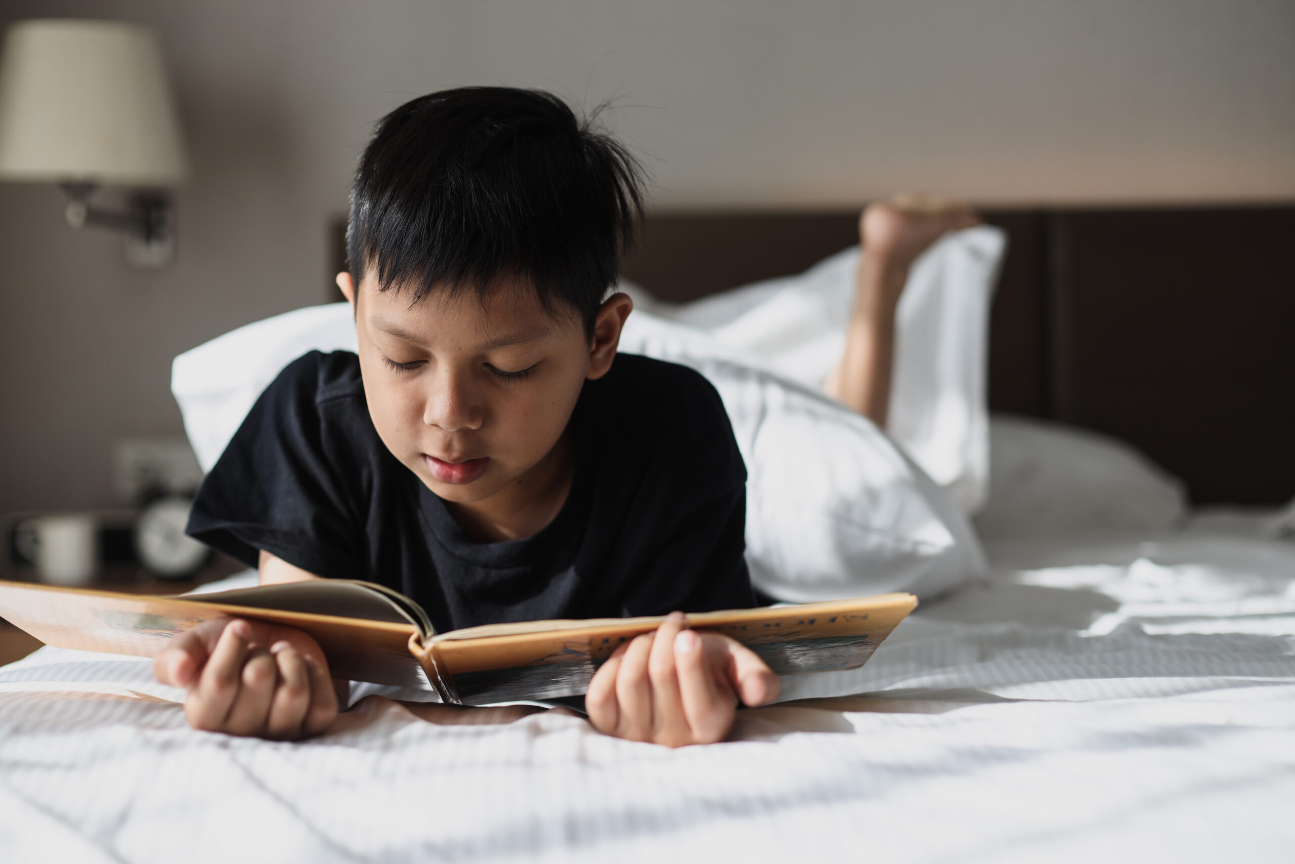 asian-boy-reading-a-book-on-bed-2021-09-04-03-08-12-utc