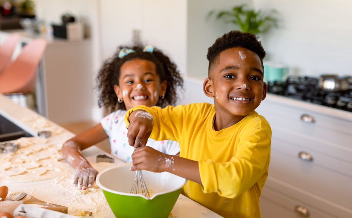 Happy african american siblings baking in kitchen. baking and cooking, childhood and leisure time at home.