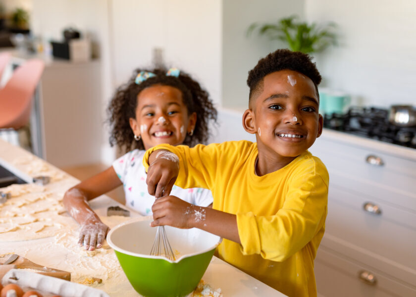 Happy african american siblings baking in kitchen. baking and cooking, childhood and leisure time at home.