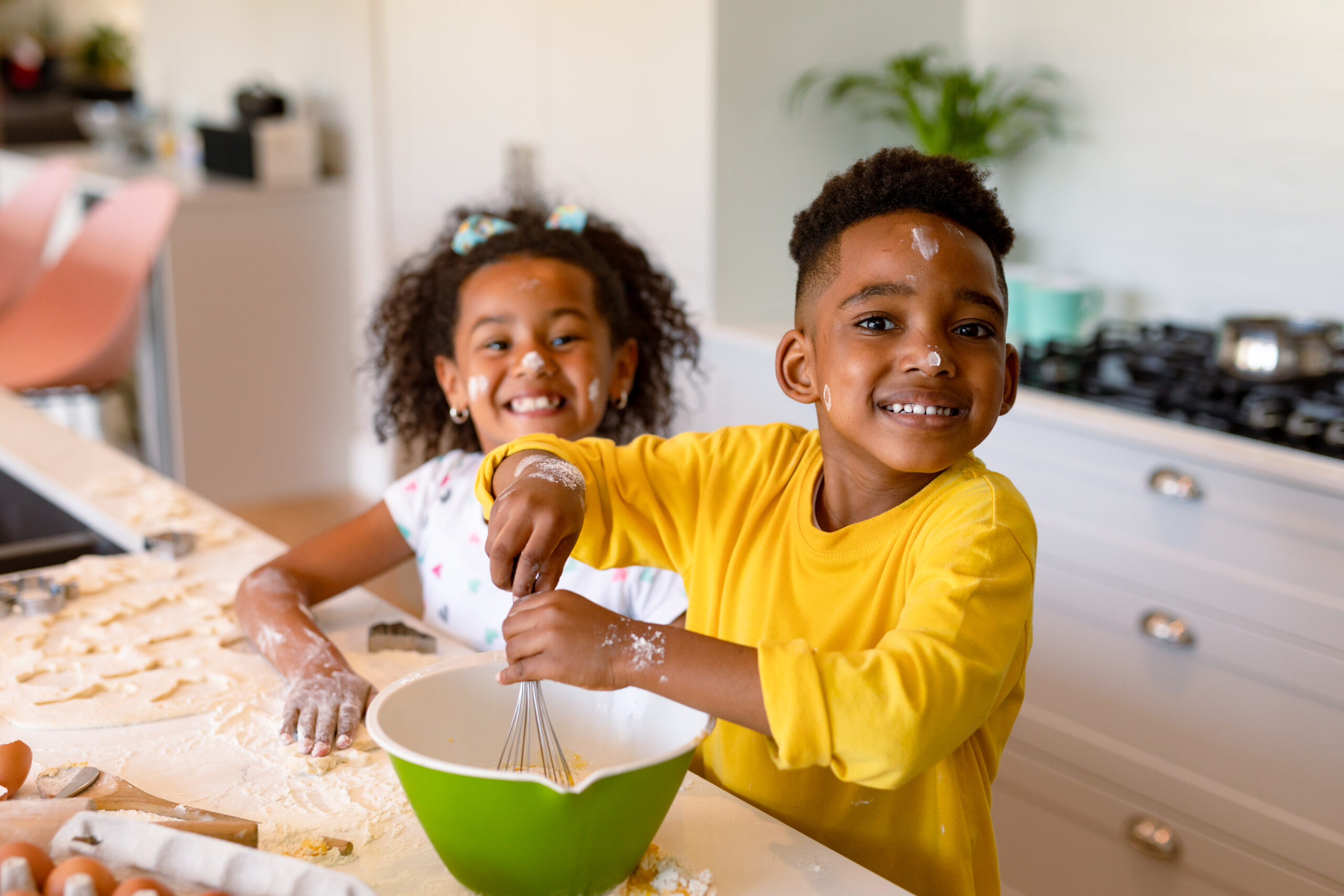 Happy african american siblings baking in kitchen. baking and cooking, childhood and leisure time at home.