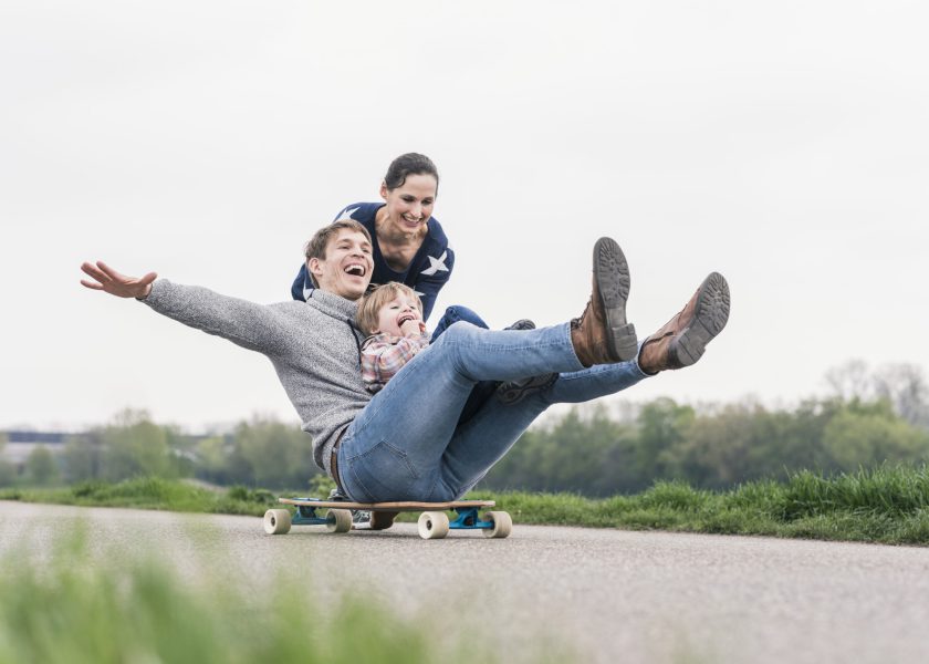 Father and son having fun, playing with skateboard outdoors
